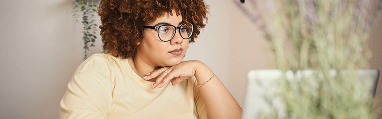 African black woman student afro hair in glasses studying online working on laptop computer at home office workspace.-1