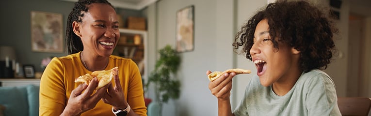 Mother and teenage son having pizza at home