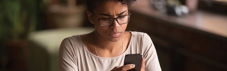 Upset confused african woman holding cellphone having problem with phone