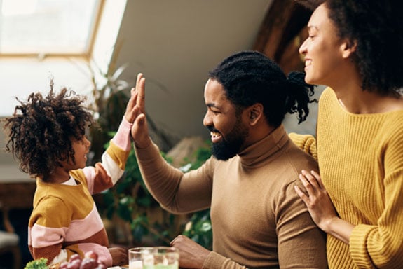 Family-celebrating-debt-consolidation-success-with-a-high-five-while-smiling-at-each-other-in-sweaters.