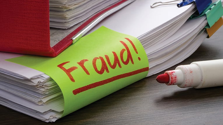 A folder and a stack of papers about finances or taxes with an inscription fraud