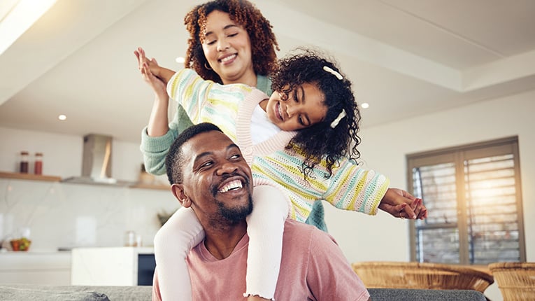 Black family, father and daughter playing with mother on living room sofa together for fun bonding at home.