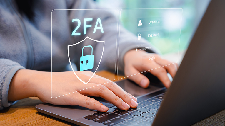 Two-Factor Authentication for Cyber Security. Person using a laptop with a digital screen displaying a shield icon and 2FA representing two-factor authentication and enhanced cyber security measures