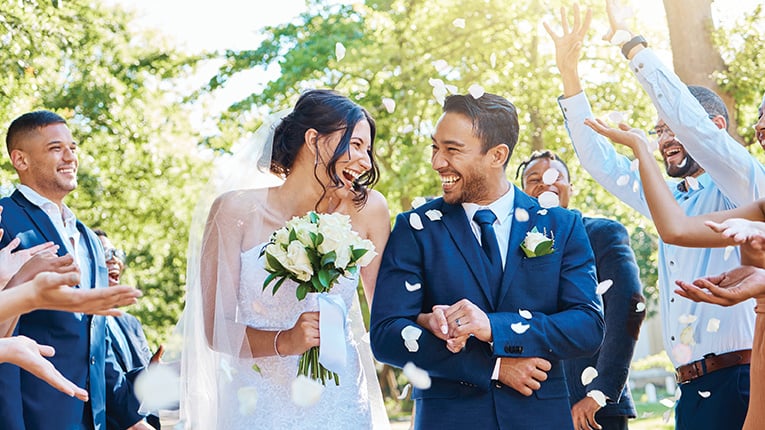 Wedding guests throwing rose petals confetti tradition over bride and groom on their special day.