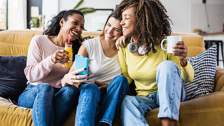 Cheerful multiracial female friends enjoying free time together at home